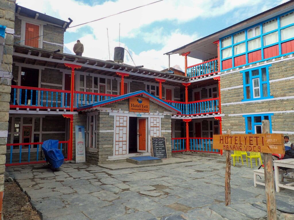 Image of a stone square surrounded by colorful accommodation buildings in Nepal. Staying in locally owned accommodation can make your trip more sustainable. 
