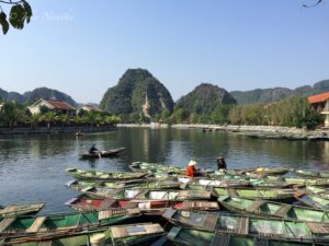 Image of many wooden boats floating on calm waters with lush hills in background in Northern Vietnam.