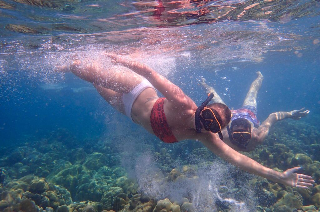 Underwater image of two snorkelers above a reef. 