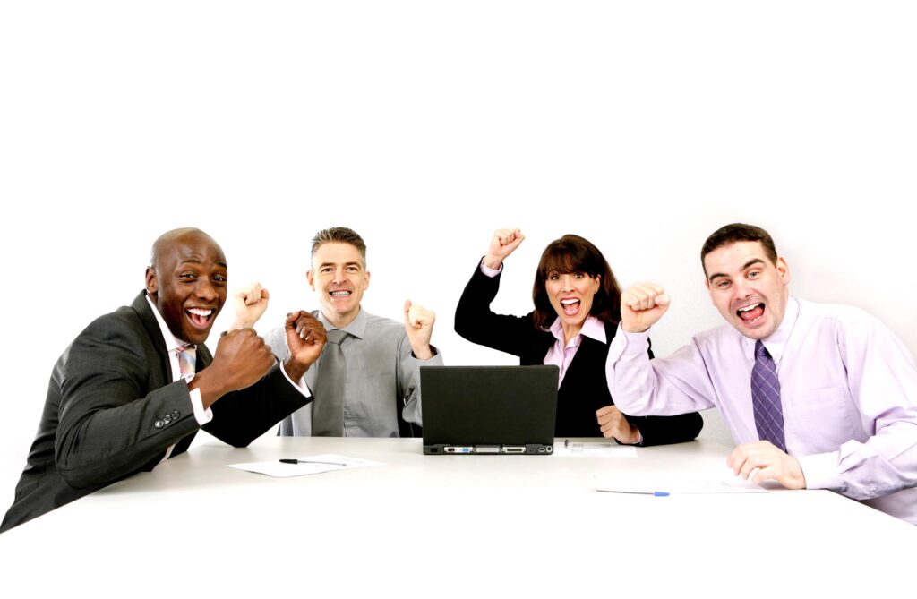 Image of four people at a conference table with a laptop with expressions of happiness and accomplishment. Studies show that happy employees are more productive.