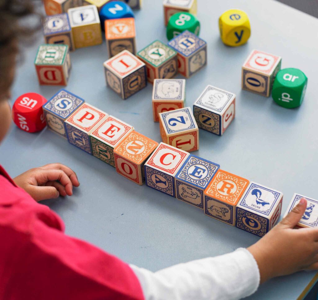Image of a child playing with wooden letter blocks.