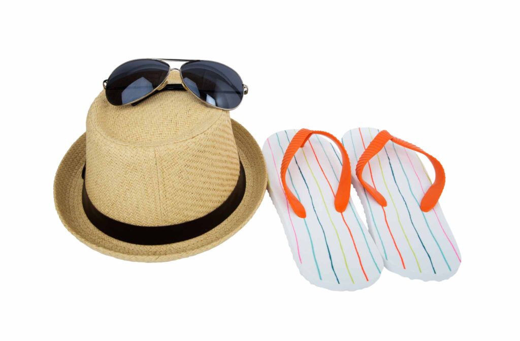 Image of a straw fedora, sunglasses and flip flops. 
