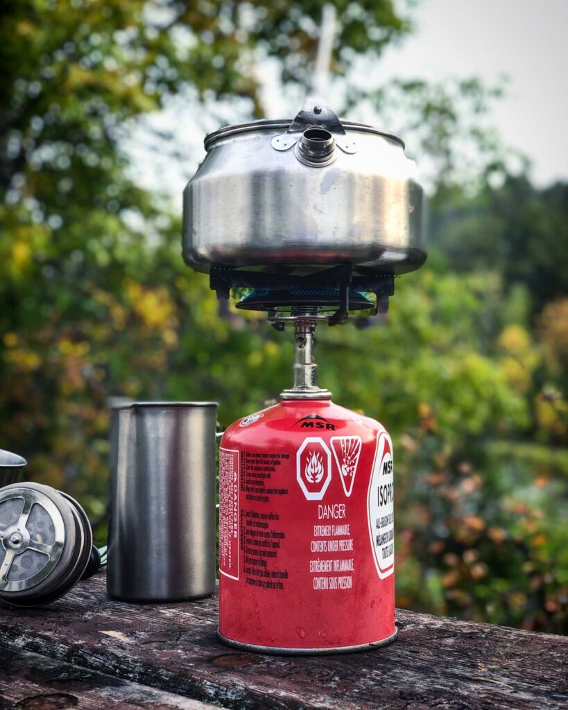 Image of a small camp stove with pot sitting atop a fuel canister.