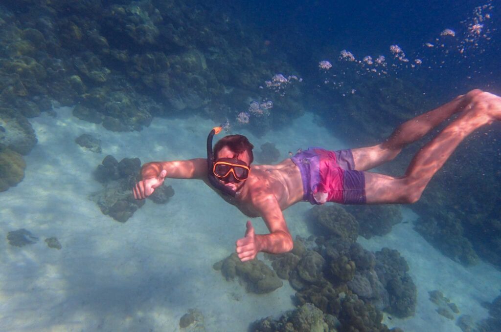 Image of a snorkeler underwater giving two thumbs up. Using eco-friendly sunscreen is an environmentally sustainable choice.