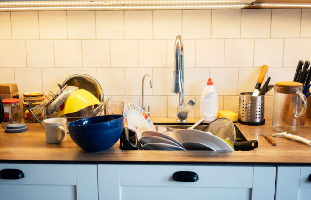 Image of a kitchen sink surrounded by dirty dishes. Giving children routine tasks and chores teaches responsibility, which can lead to more sustainable lifestyle choices.