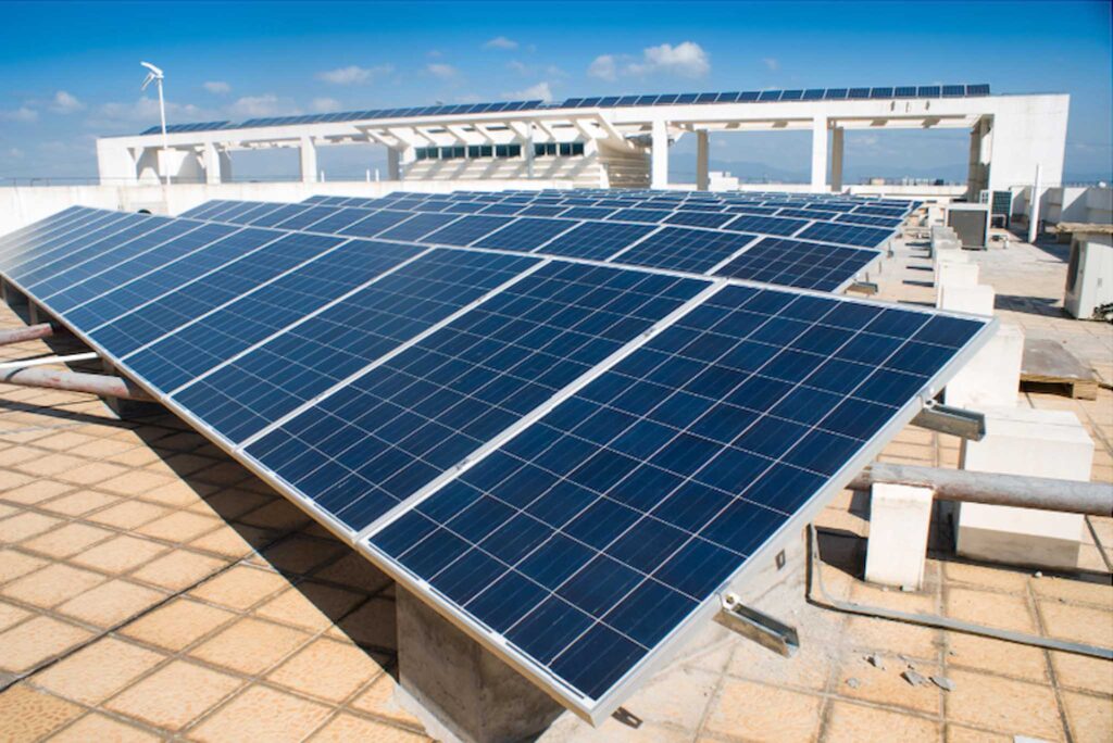 Image of two large solar panels on a flat roof on a sunny day. Switching to solar power can make schools more sustainable.