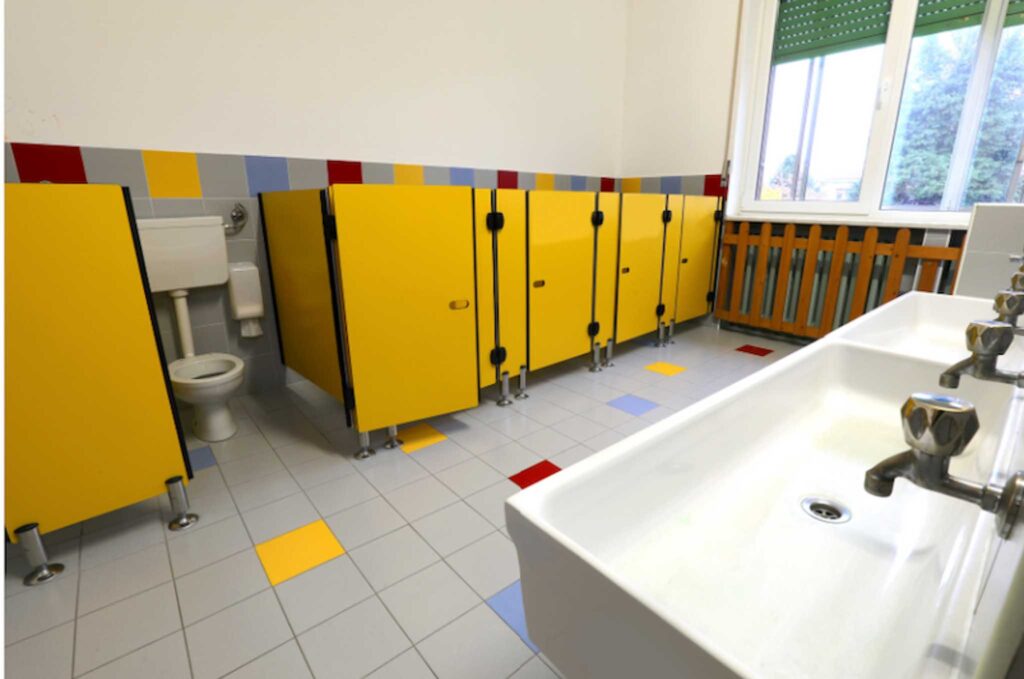 Image of a school washroom with brightly coloured yellow doors. Installing low-flow toilets and sinks will help school be more sustainable.
