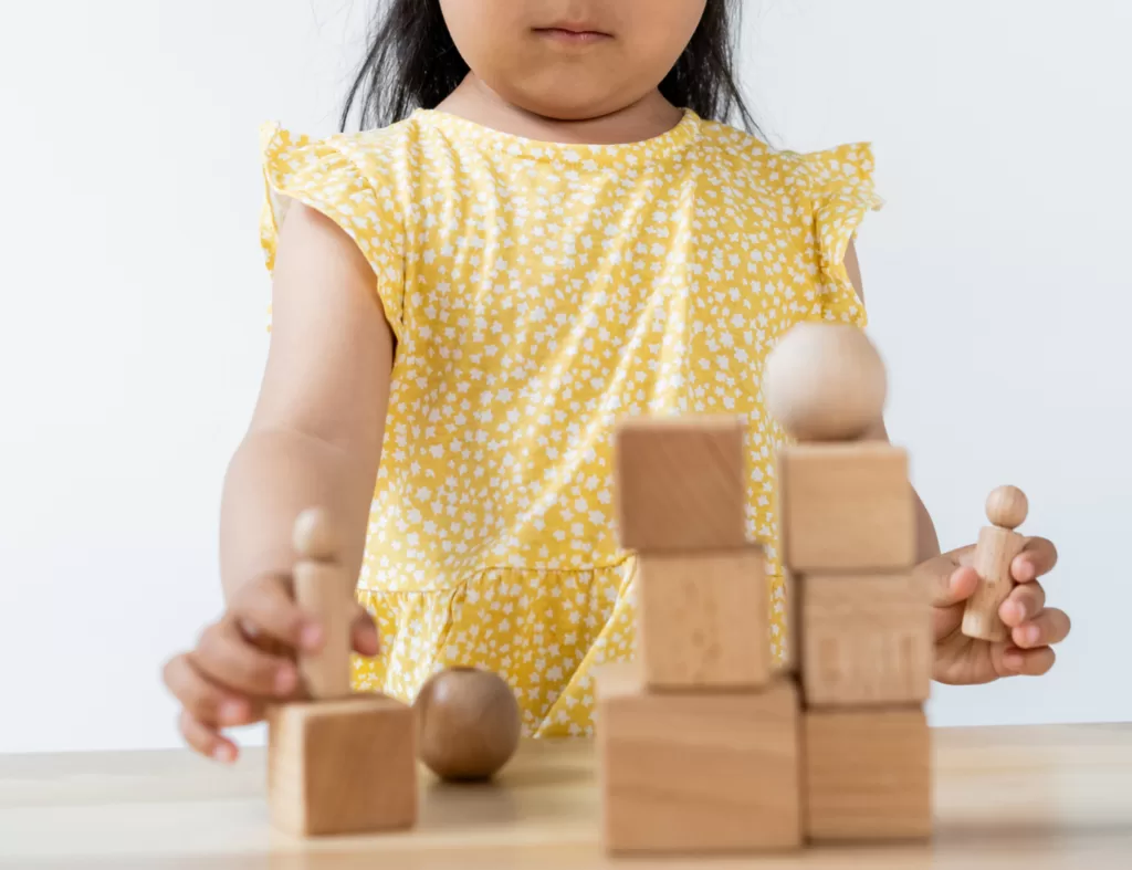 Image of a young child playing with wooden blocks. Eco-child's play is essential for a sustainable lifestyle.