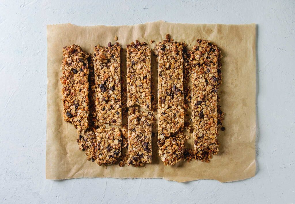 Image of five homemade energy bars laying side by side on a beeswax wrapper. Making your own oat bars with eco-friendly packaging can make your camping trip more sustainable.