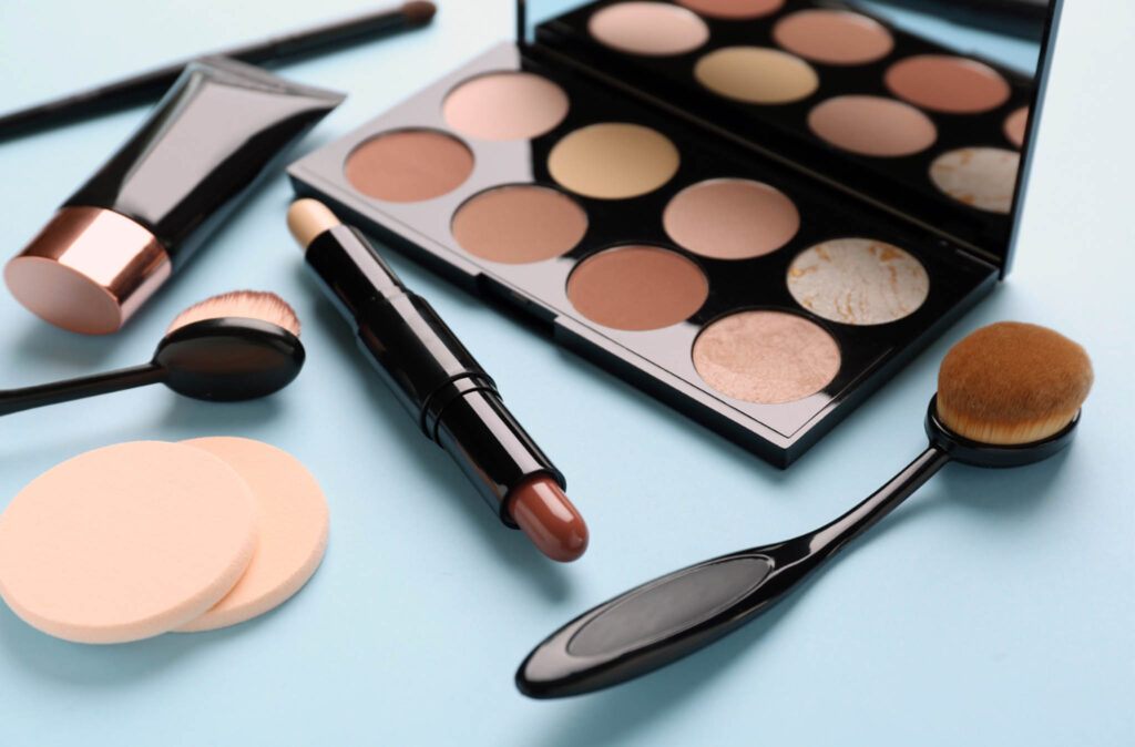 Image of cosmetic items including an eyeshadow palette, eyeliner, make up pads and brushes.