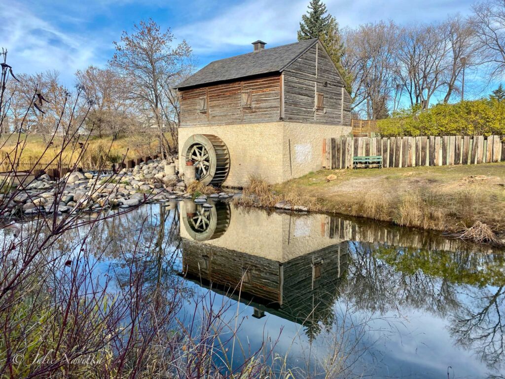 Image of an old mill reflected in the water before it. Protecting waterways is essential in an eco-friendly park