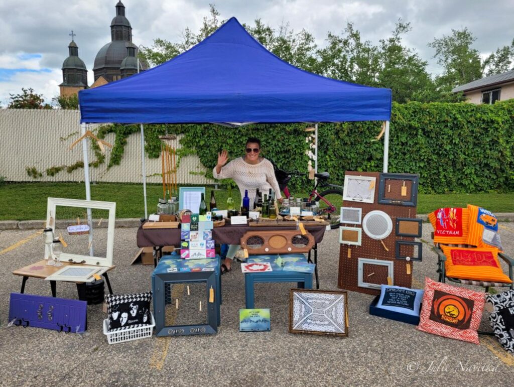Image of website author at a market stall surrounded by their upcycled creations. 