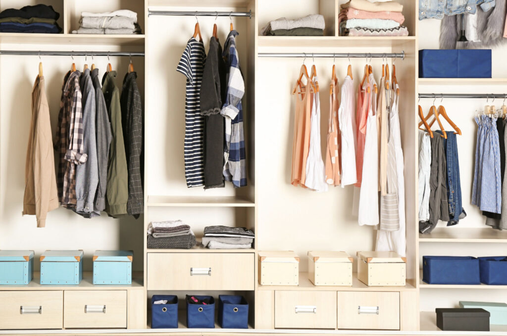 Image of a well-organized, brightly lit minimalist closet. A capsule wardrobe is a perfect way to make your work clothing more sustainable.
