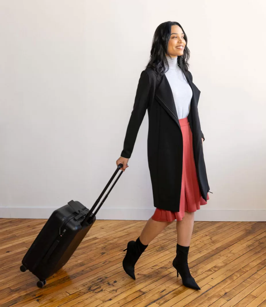 Image of a woman dressed in business attire by Encircled pulling a rolling suitcase.