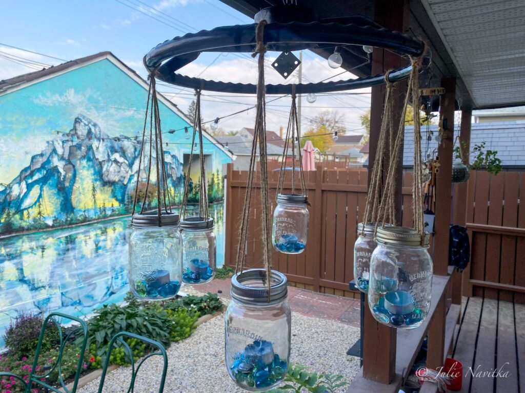 Image of a chandelier made from mason jars, twine, and an old automobile steering wheel hanging on a back porch. Creating new items from old objects by upcycling keeps them from ending up in the landfill.