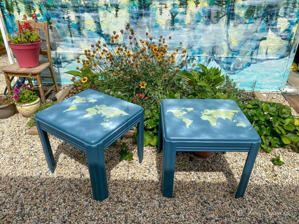 Image of two end tables refinished in blue paint, each with a stenciled image of a map of the Earth on the top.