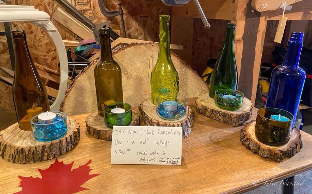 Image of candle holder/displays made from wine bottles and wooden rounds. Glass is sometimes broken down when recycled, which requires energy use, unlike upcycling.