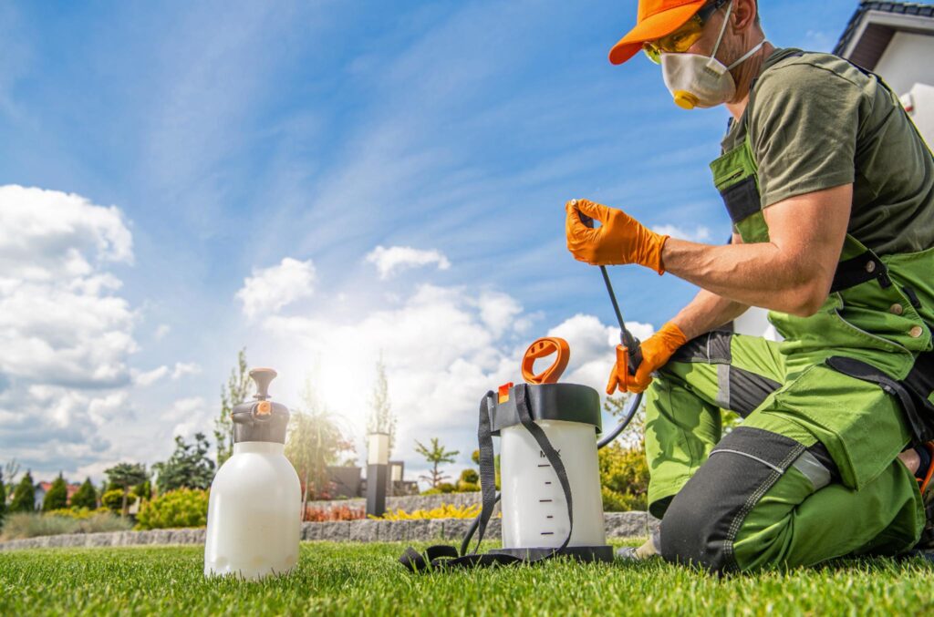 Image of a person wearing protective gear preparing chemicals to spray on a lawn of grass. One of the problems with turf grass lawns is the amount of chemicals that runoff of them into our water system.