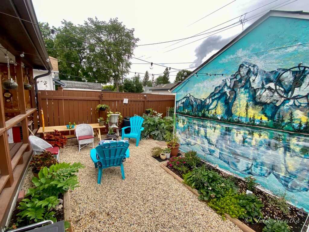 Image of a small grass-free backyard featuring flower and vegetable gardens and pea gravel ground cover. 