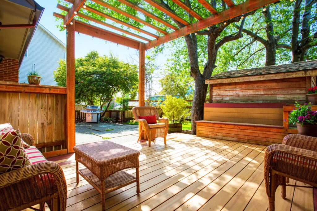 Image of a large backyard deck featuring a seating space and pergola. 