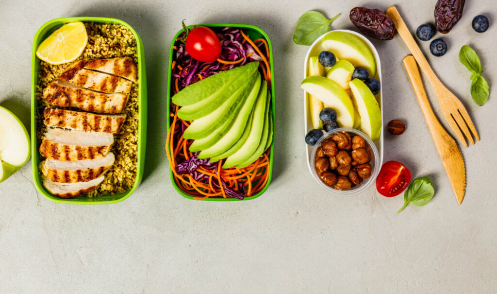 Image of three healthy lunches from above packed in containers with a set of bamboo utensils. Packing your lunch in an eco-friendly lunch box reduces plastic waste.