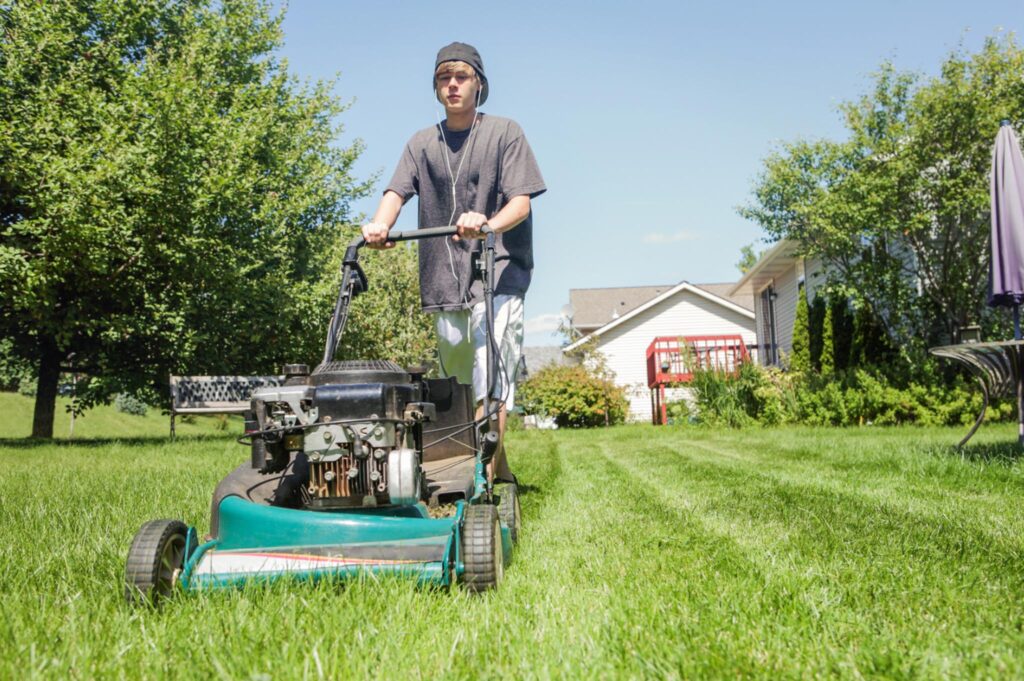 Image of a teenage mowing the lawn.