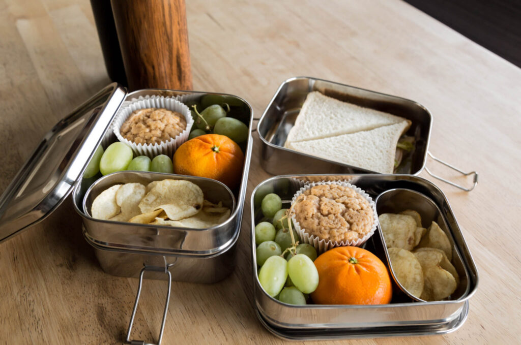 Image of lunches packed in durable stainless steel containers. Avoid plastics when purchasing lunch boxes and bags.