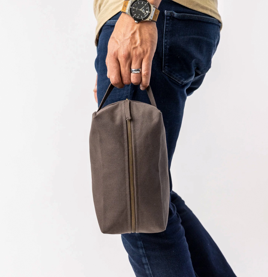 Image of a person carrying the Sustainable Toiletry Bag by Terra Thread by their side.