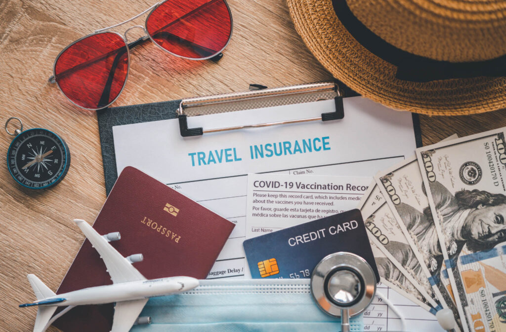 Image of travel documents and necessities on a tabletop, such as passports, credit card, cash, sunglasses, etc. These items need to be included when packing for a year of travel.