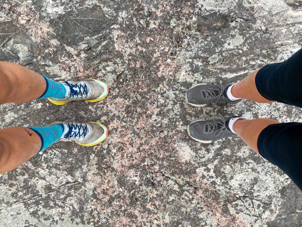 Image of two pairs of hiking shoes worn by two different hikers, taken from above.