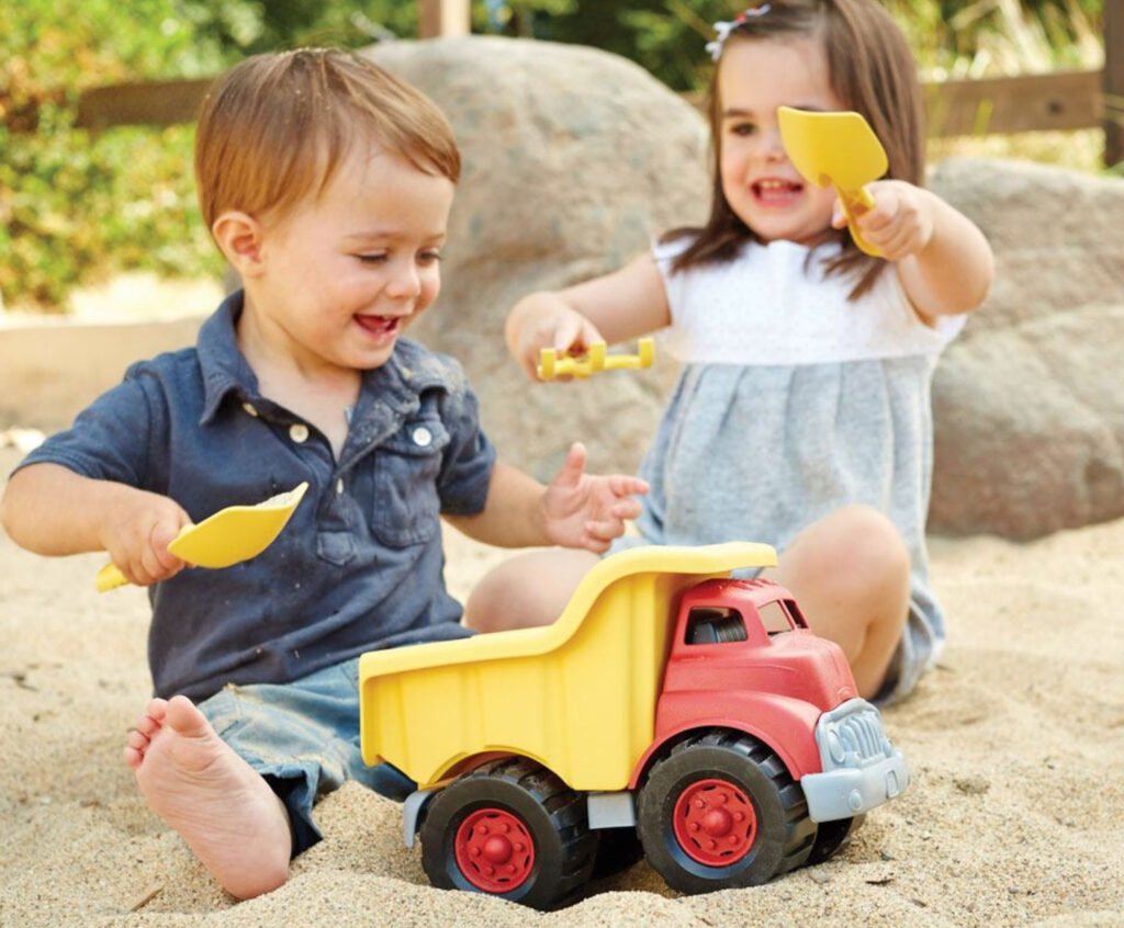 Image of two toddlers playing with the Green Toys Dump Truck in the sand.