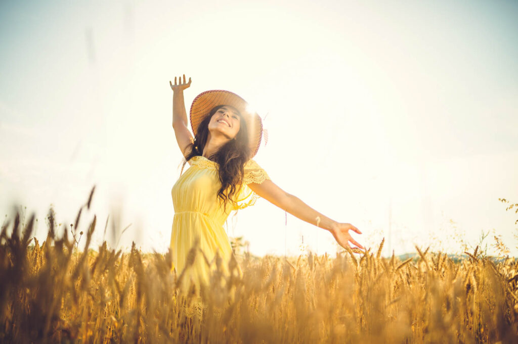 Image of a woman in field with her arms out bathed in golden light.
