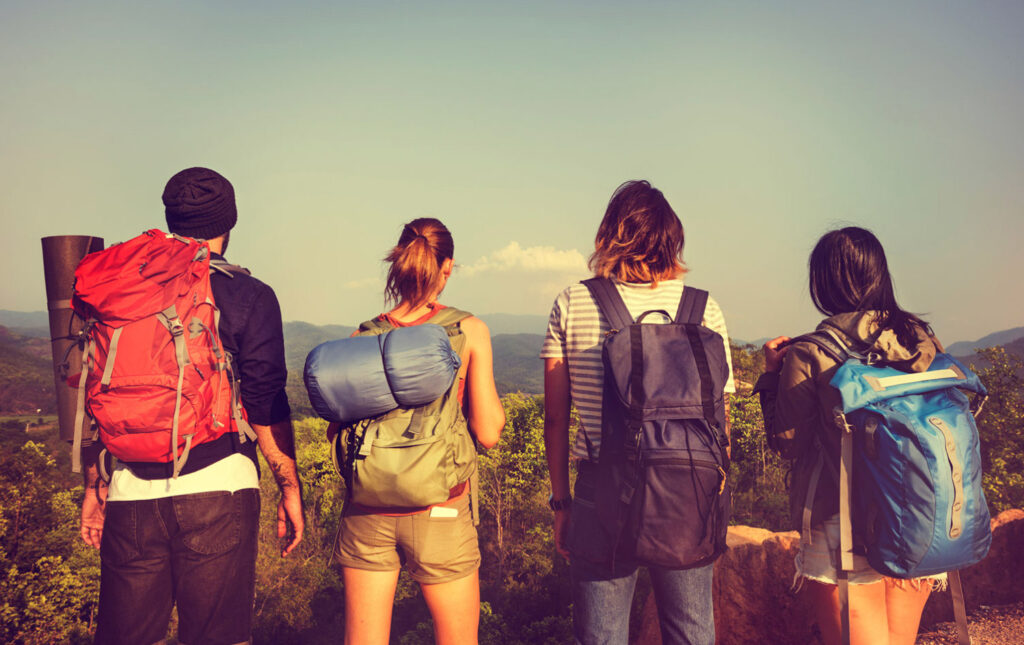 Image of four hikers taken from behind looking out over a view. Environmentally-friendly backpacks should be a priority for outdoor lovers!