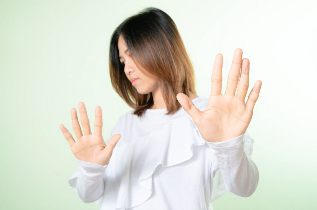 Image of a person with their hands up and out in refusal at the camera.