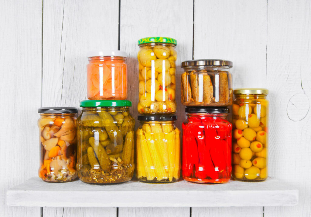 Image of 8 glass jars filled with various preserved food products. 