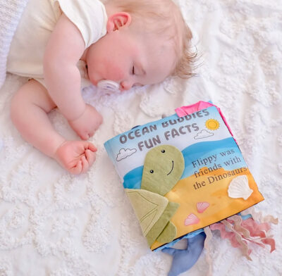 Image of a sleeping baby next to the Tikiri Ocean Activity Book