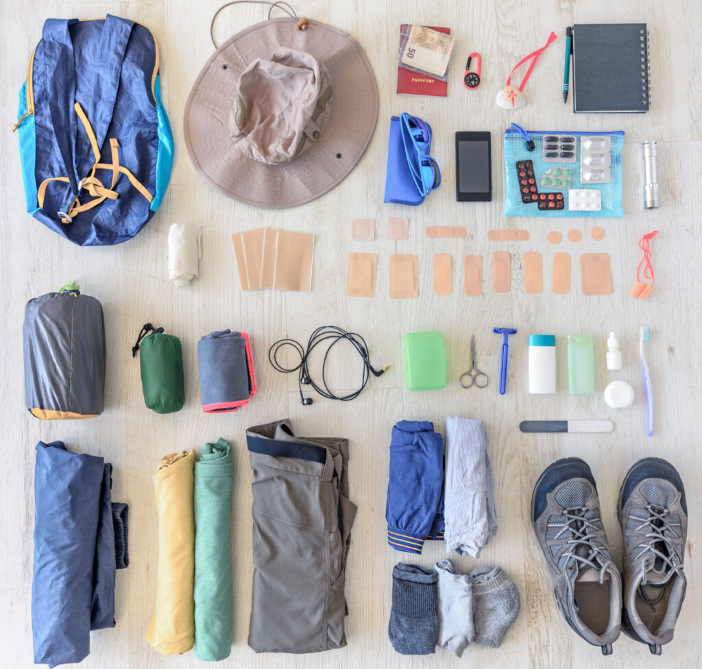 Image of neatly organized camping clothing and gear laid on a table and taken from above. Choosing eco-friendly hiking gear is part of sustainable recreation.