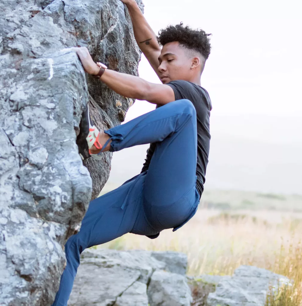 Image of a man rock climbing wearing the Trailhead pant by Coalatree