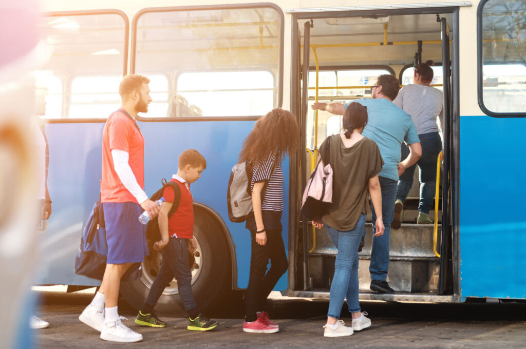 Image of people of various ages boarding a city transit bus. Taking public transportation can help you create an environmentally friendly work commute.