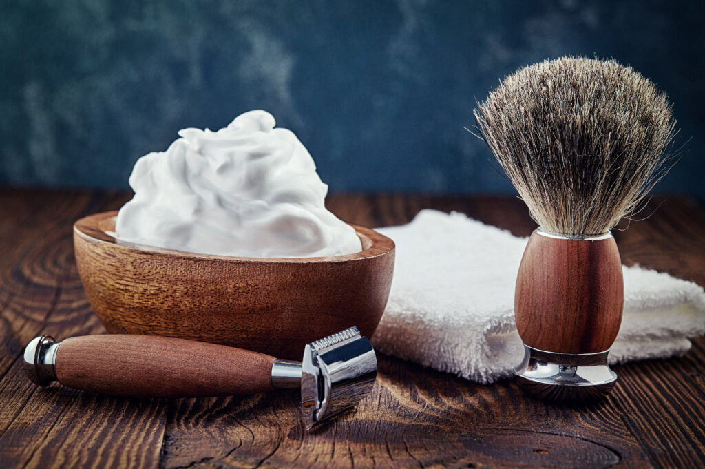Image of a shaving set with brush, razor, towel, and bowl filled with shaving soap lather.