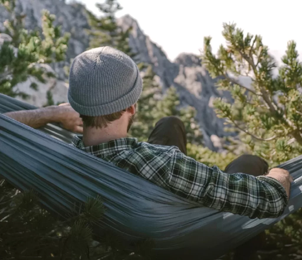Image taken from behind of a man in a hammock surrounded by greenery. The tree hugger in your life would probably love an eco-friendly gift from Coalatree!