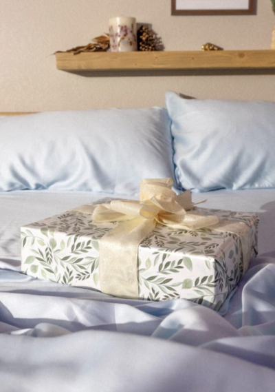 Image of a wrapped gift on an unmade bed with blue sheets.