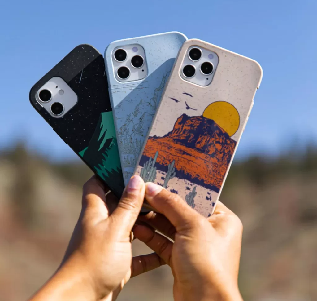 Image of a pair of hands holding up three different styles and designs of eco-friendly phone cases from Pela.