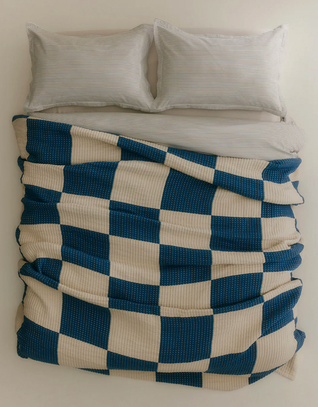 Image of a comforter and sheet set made by Kotn on a bed. 