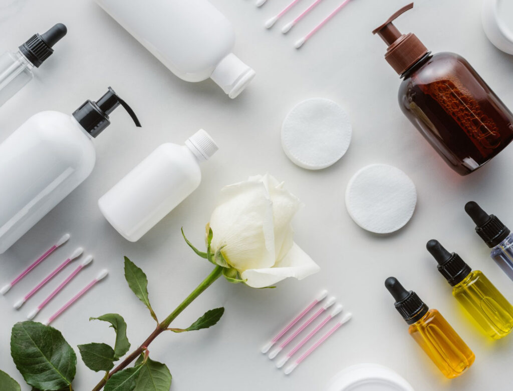 Image of a variety of cosmetics and beauty products taken from above on a white surface. Supporting vegan cosmetic brands can help you be a conscious consumer.