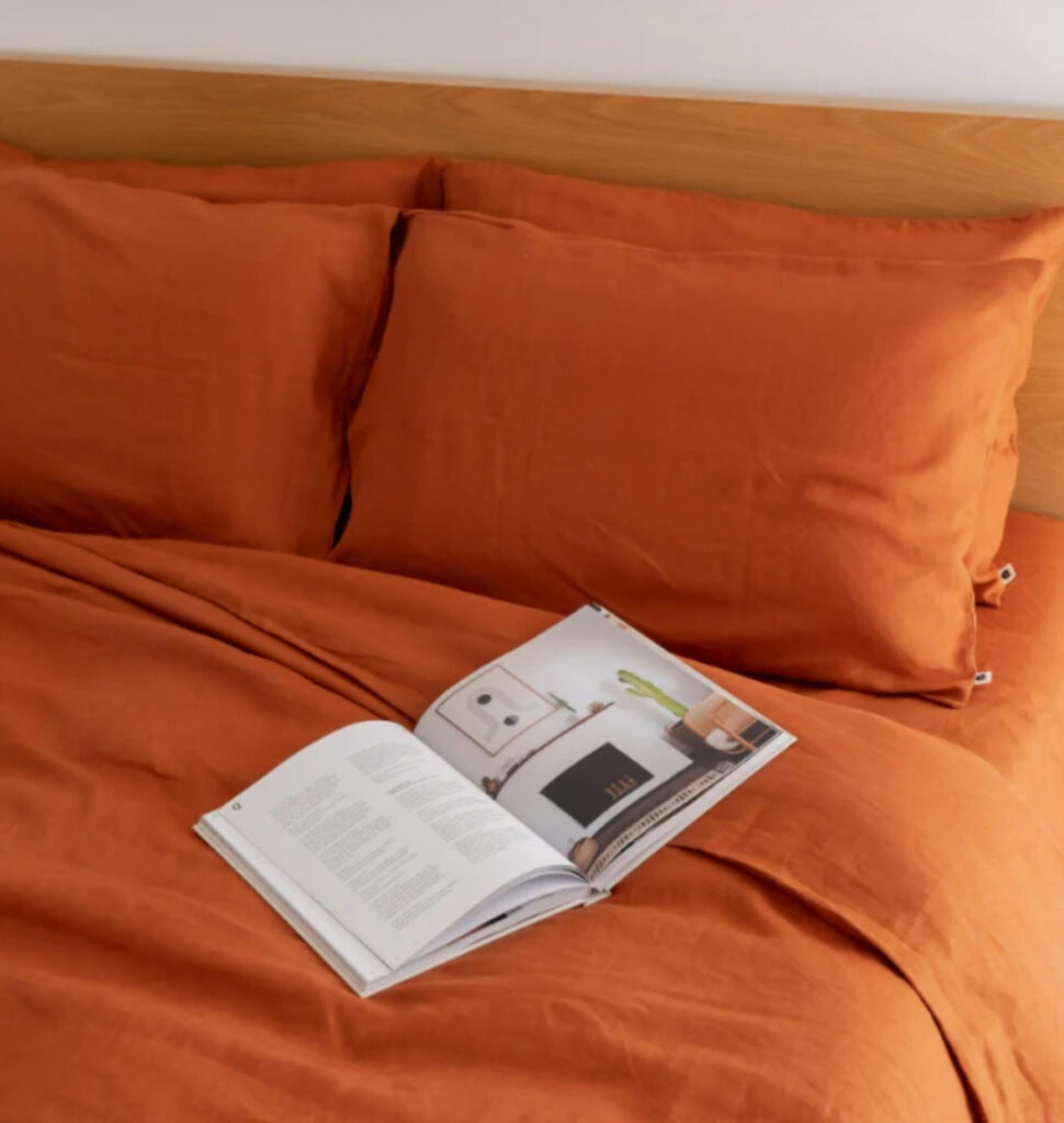 Image of a bed with hemp sheets and pillow cases in a burnt orange colour from Eva.