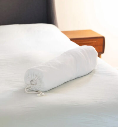 Image of the Leaf Score Essentials mattress protector in its cotton bag sitting on a clean bed.
