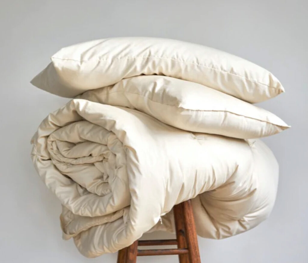 Image of a duvet and two pillows by Takasa sitting atop a wooden stool. 