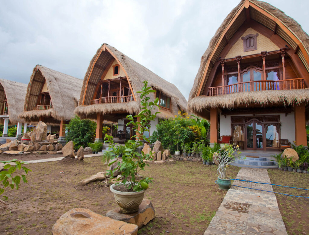 Image of some grass-roofed huts on the beach. Some eco resorts make it feel like you are camping in luxury!