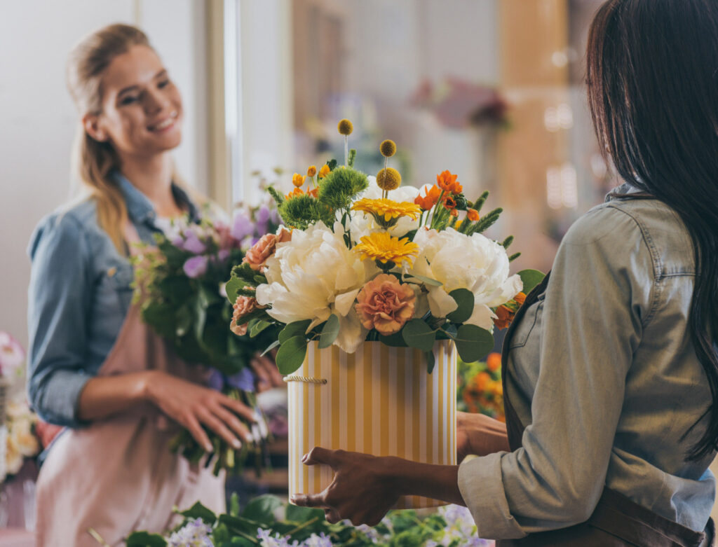 Image of a woman holding a basket of flowers at a florist. Ethical sourcing for small businesses is essential.